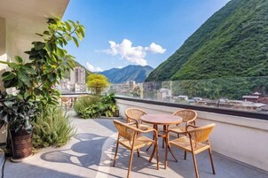 Una terraza con mesa y sillas, con vista a un paisaje montañoso.