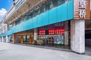 Un edificio con una amplia fachada de vidrio y una entrada destacada con un letrero rojo.