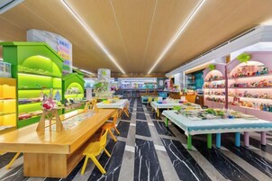 Un espacio interior luminoso con mesas, sillas, estanterías repletas de objetos y un suelo estampado.