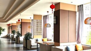 Una moderna hall d'albergo con zone relax, una reception e elementi decorativi come lanterne rosse.
