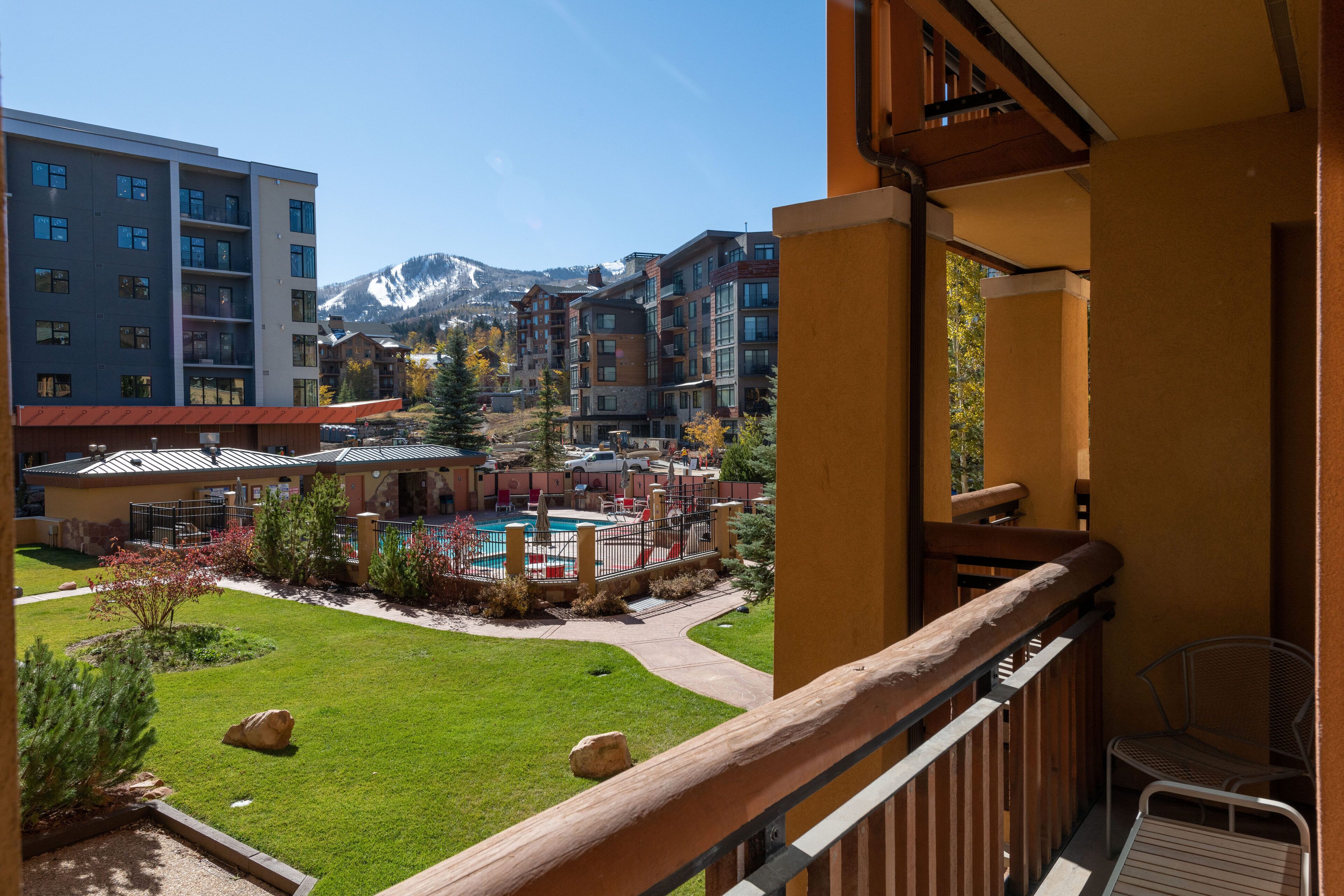 Un patio de hotel con piscina, rodeado de edificios de varios pisos y una montaña al fondo.