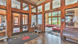 A lobby with wooden beams, a golf/bike lounge, a red sofa, and a cart. - Sundial Lodge (Park City)