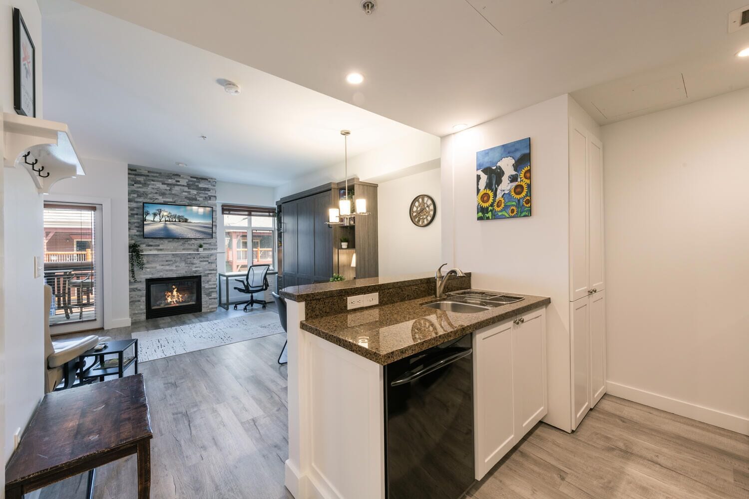 A modern kitchen with granite countertops, a dishwasher, and a built-in oven. There is a dining area with a table and chairs, and a fireplace.