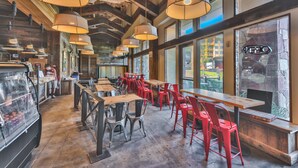 A restaurant with high ceilings, exposed beams, and large windows. Tables and chairs are arranged for dining. - Sundial Lodge (Park City)