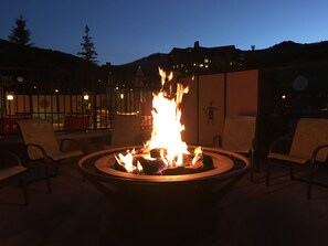 A fire pit with flames in the center, surrounded by chairs. - Sundial Lodge (Park City)