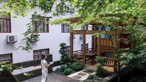 A courtyard with a wooden pergola, stone steps, and a small garden area. - Chabofu Charenju Hotel (Wuyuan)