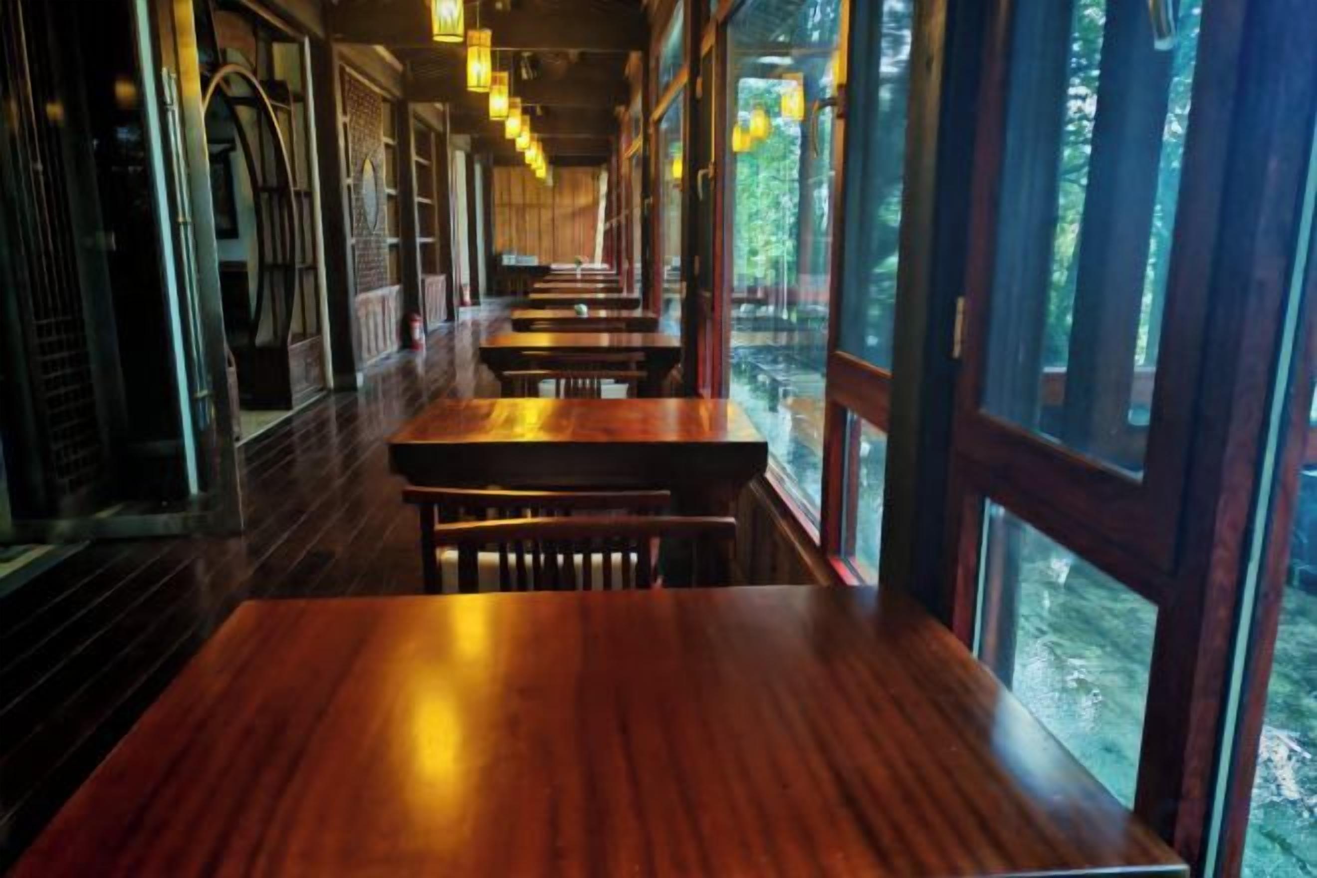File di tavoli e panche di legno in un ristorante con ampie vetrate.