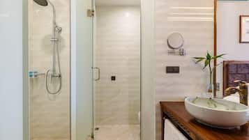 A modern bathroom with a glass-enclosed shower, a wooden vanity with a large vessel sink, and a mirror above the sink.