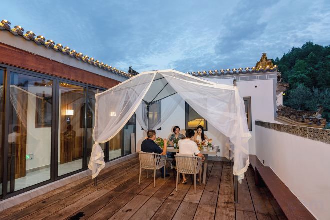 A covered outdoor seating area with a table and chairs, a glass enclosure, and a white canopy.