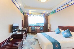 A hotel room with a bed, a desk, a chair, a TV, and a view of the city. - Chabofu Charenju Hotel (Wuyuan)