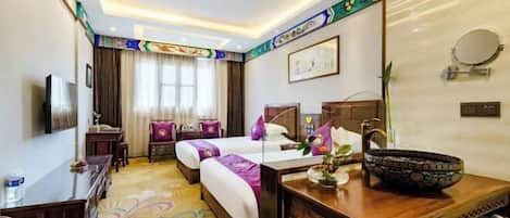 A hotel room with a bed, bedside tables, a desk, a mirror, and a decorative bowl on the desk.