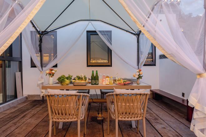 A tented dining area with a table, chairs, and a window.
