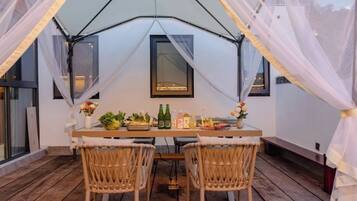 A tented dining area with a table, chairs, and a window.