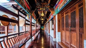 A corridor with wooden doors and a polished floor. - Chabofu Charenju Hotel (Wuyuan)