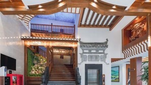 A staircase leading to a balcony with wooden railings and a decorative ceiling. - Chabofu Charenju Hotel (Wuyuan)