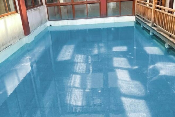 A clear indoor swimming pool with a wooden deck and glass windows. - Chabofu Charenju Hotel (Wuyuan)