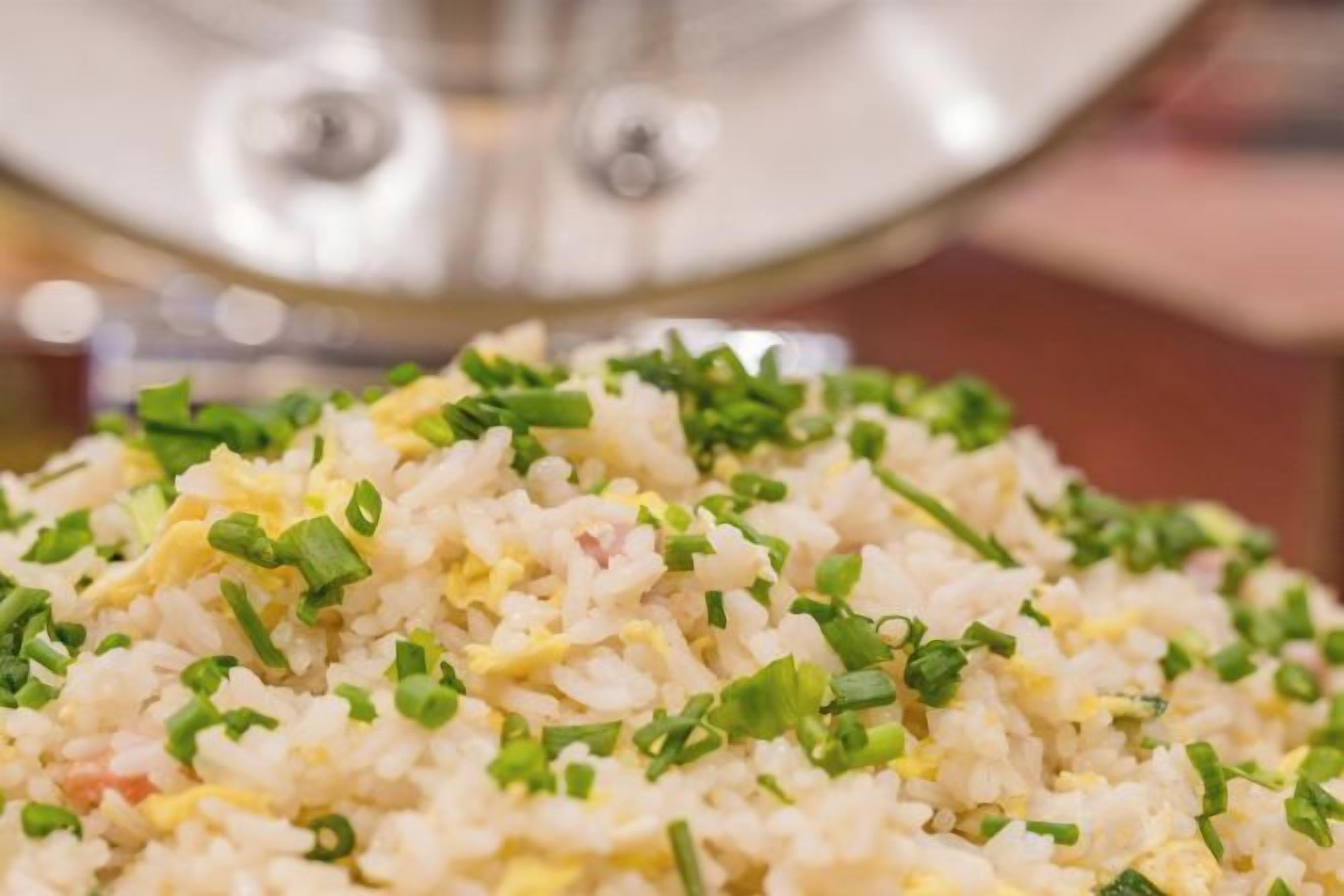 A close-up of a plate of fried rice garnished with green onions.