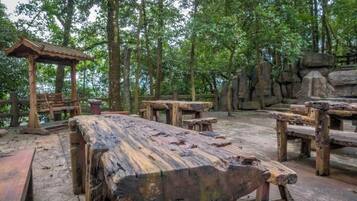 An outdoor wooden deck with benches and a gazebo, surrounded by trees and rock formations.