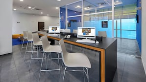 A modern conference room with a long table, multiple chairs, and two computer monitors.