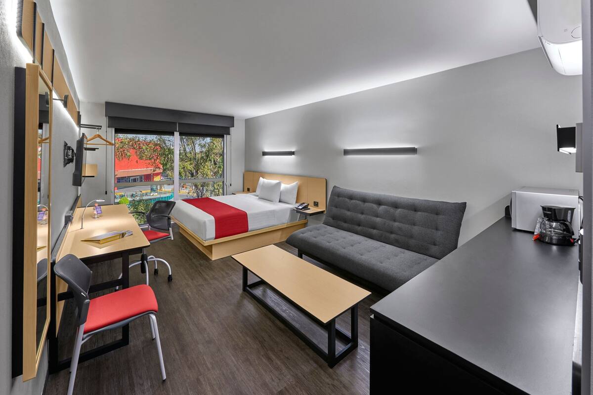 Een moderne hotelkamer met een bed, bank, bureau en stoel.
