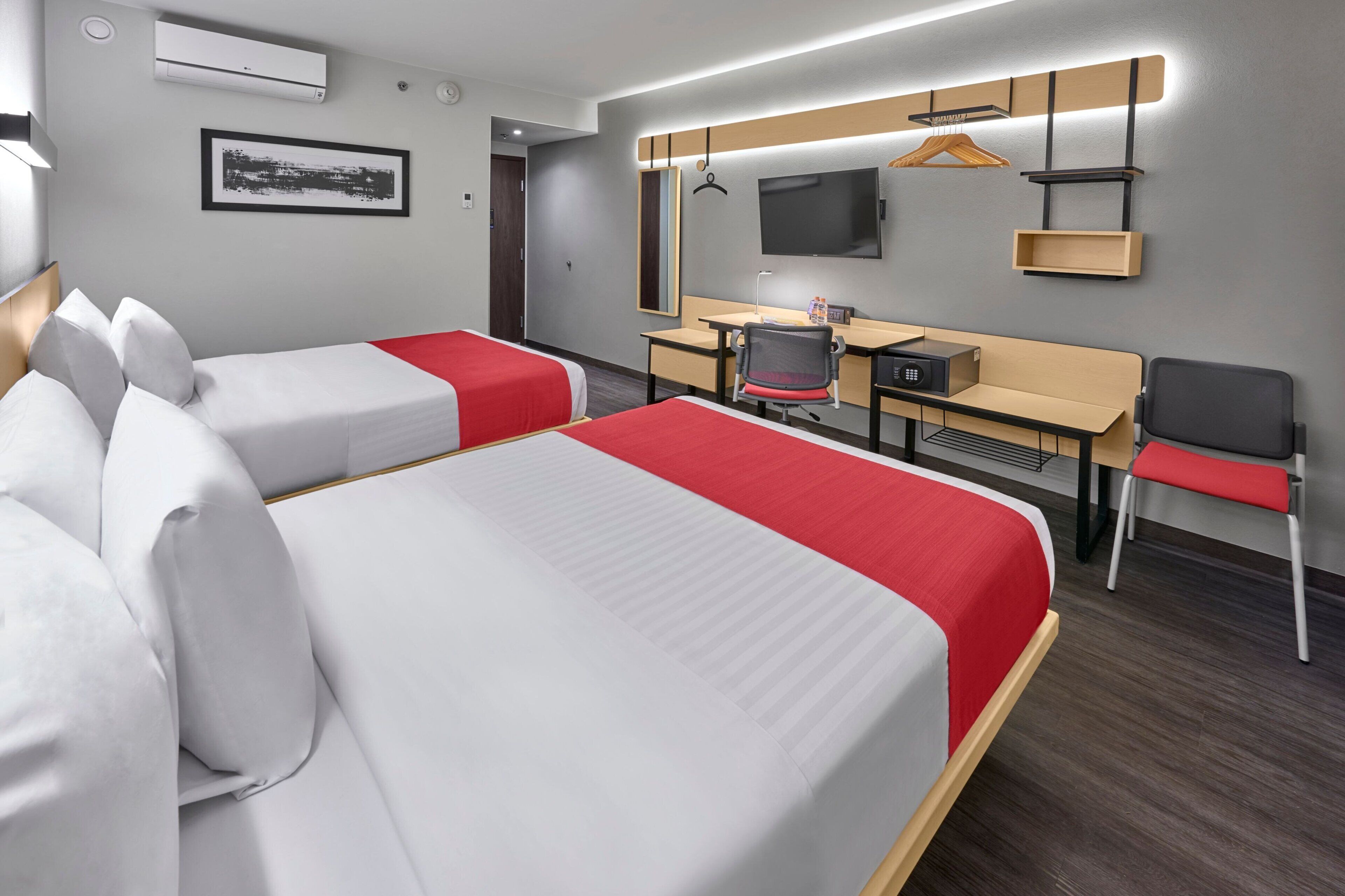 A hotel room with two beds, a desk, a chair, a television, and a mirror.
