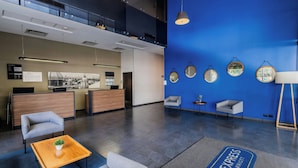 A hotel lobby with a reception desk, seating area, and a blue wall with mirrors.