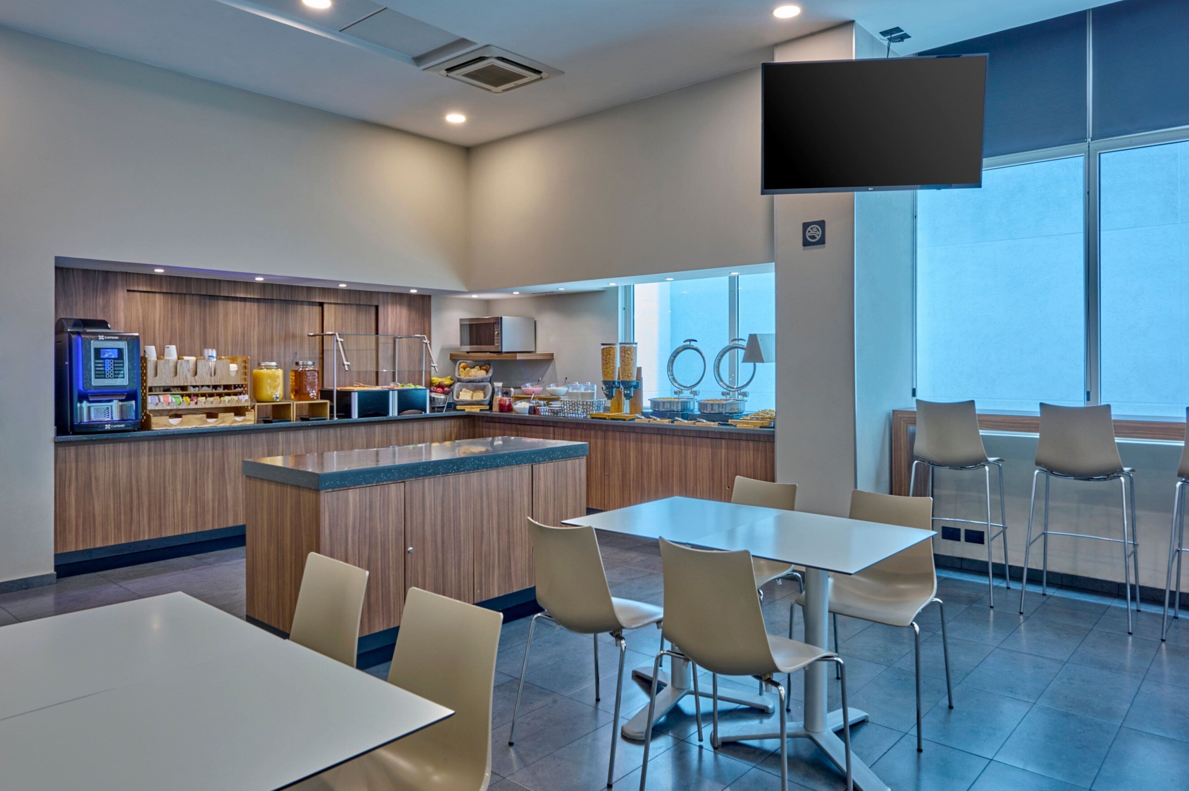 A modern cafe with a wooden counter, seating area, and large windows.