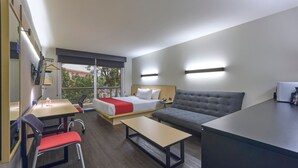 A hotel room with a bed, a sofa, a desk, and a chair.