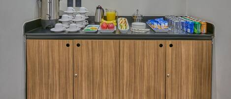 A breakfast bar with coffee, juice, and various food items.
