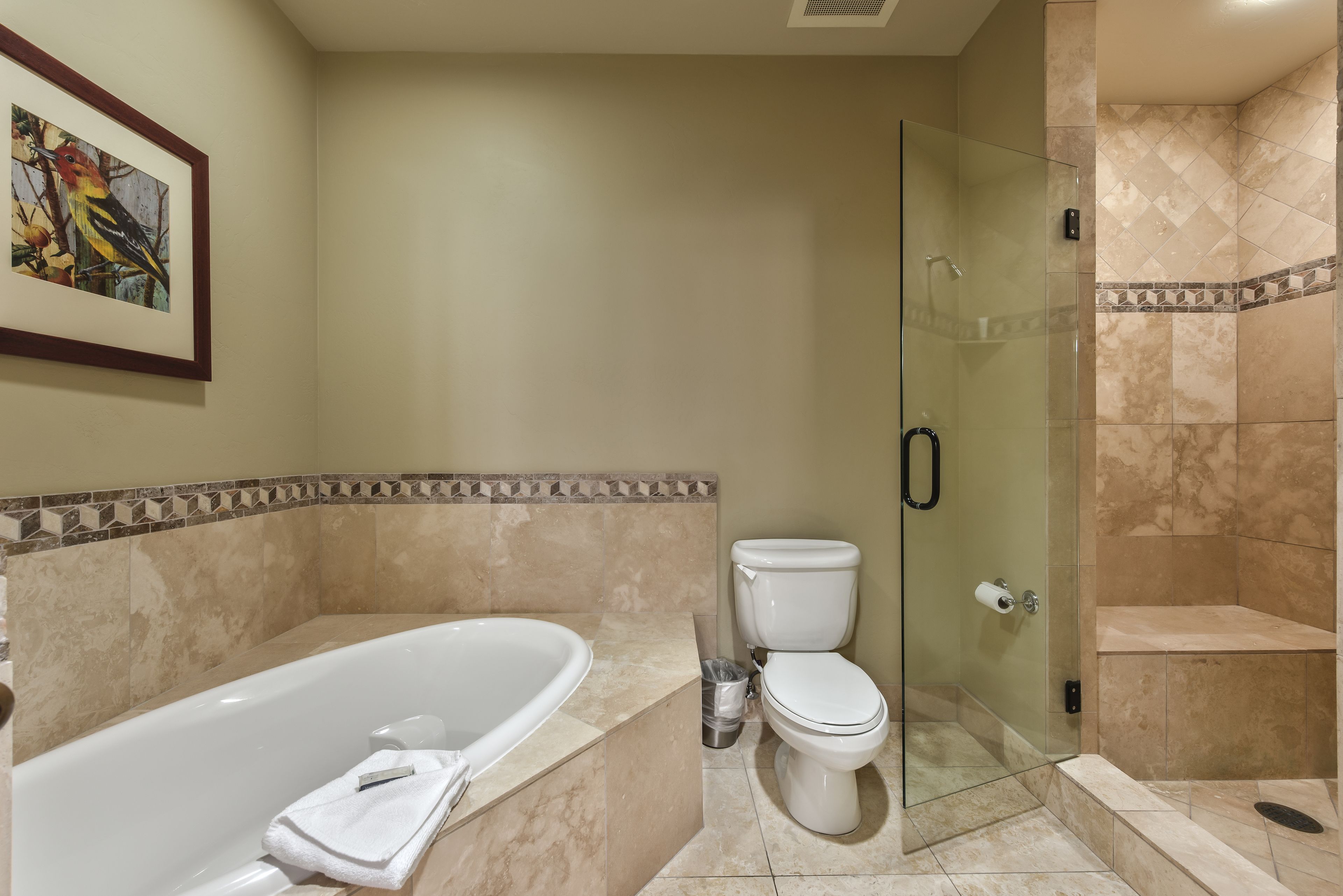 A bathroom with a bathtub, toilet, and glass-enclosed shower.