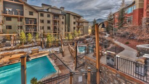 A hotel with multiple balconies, a swimming pool, and a mountainous backdrop. - Miners Club by Canyons Village Rentals (Park City)