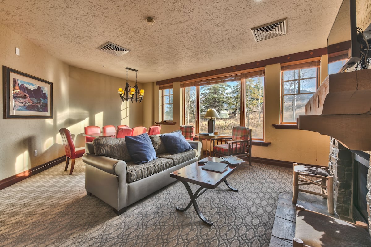 A spacious living room with a fireplace, large windows, and a cozy seating area.
