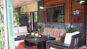 A cozy outdoor seating area with a table, chairs, and cushions. - Ataco Luxury Cabin (Concepcion de Ataco)