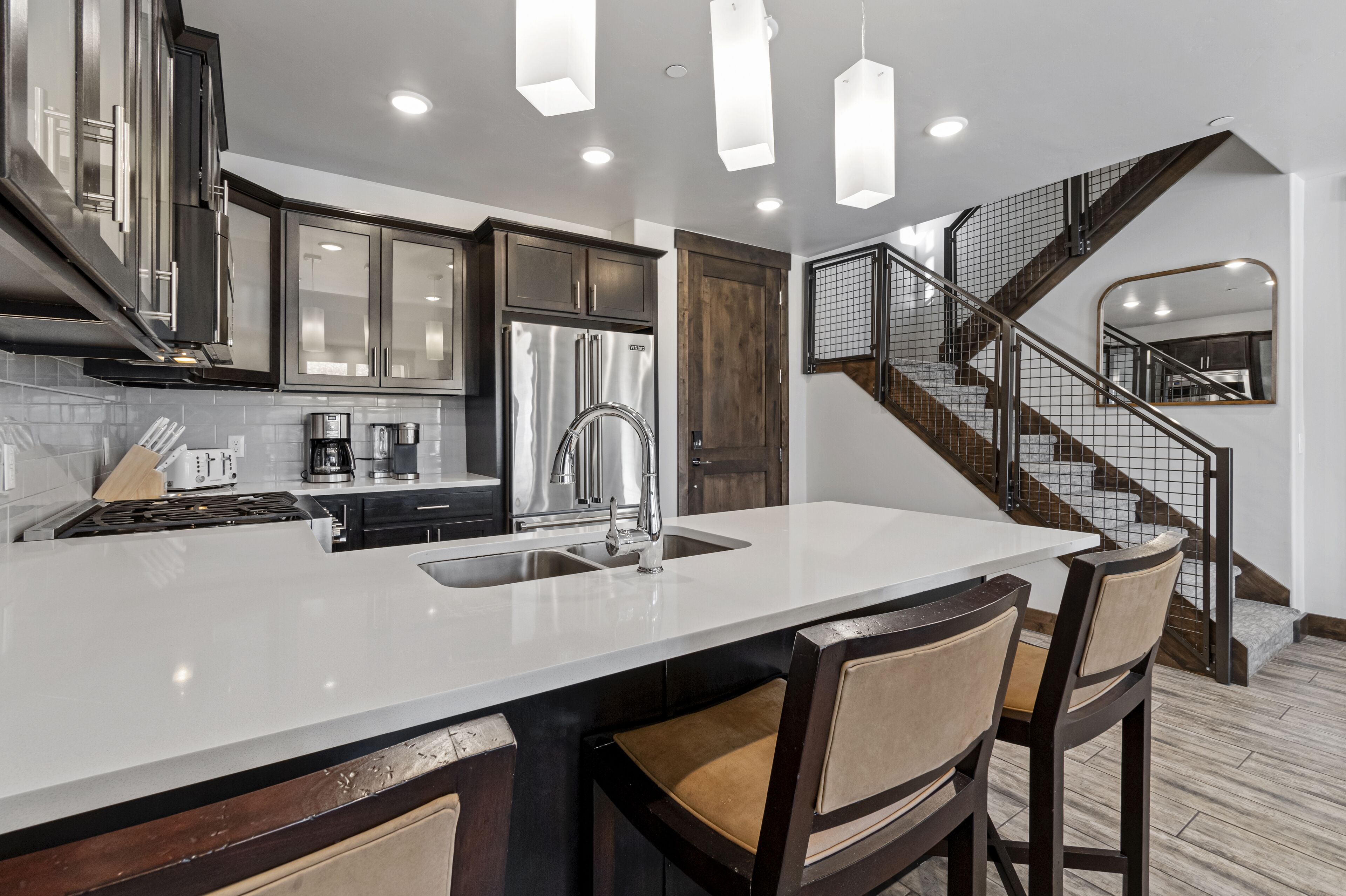 Una cocina moderna con una isla grande, electrodomésticos de acero inoxidable y una escalera que lleva a una zona tipo loft.