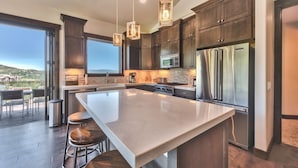 A modern kitchen with a large island, stainless steel appliances, and dark wood cabinets.