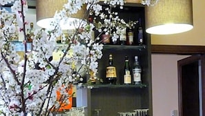 A bar area with a vase of flowers, a bottle of champagne, and glasses on a table.