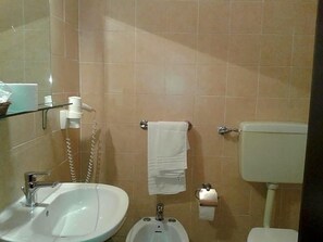 Un baño con lavamanos, bidé, inodoro y una toalla colgada en la pared.