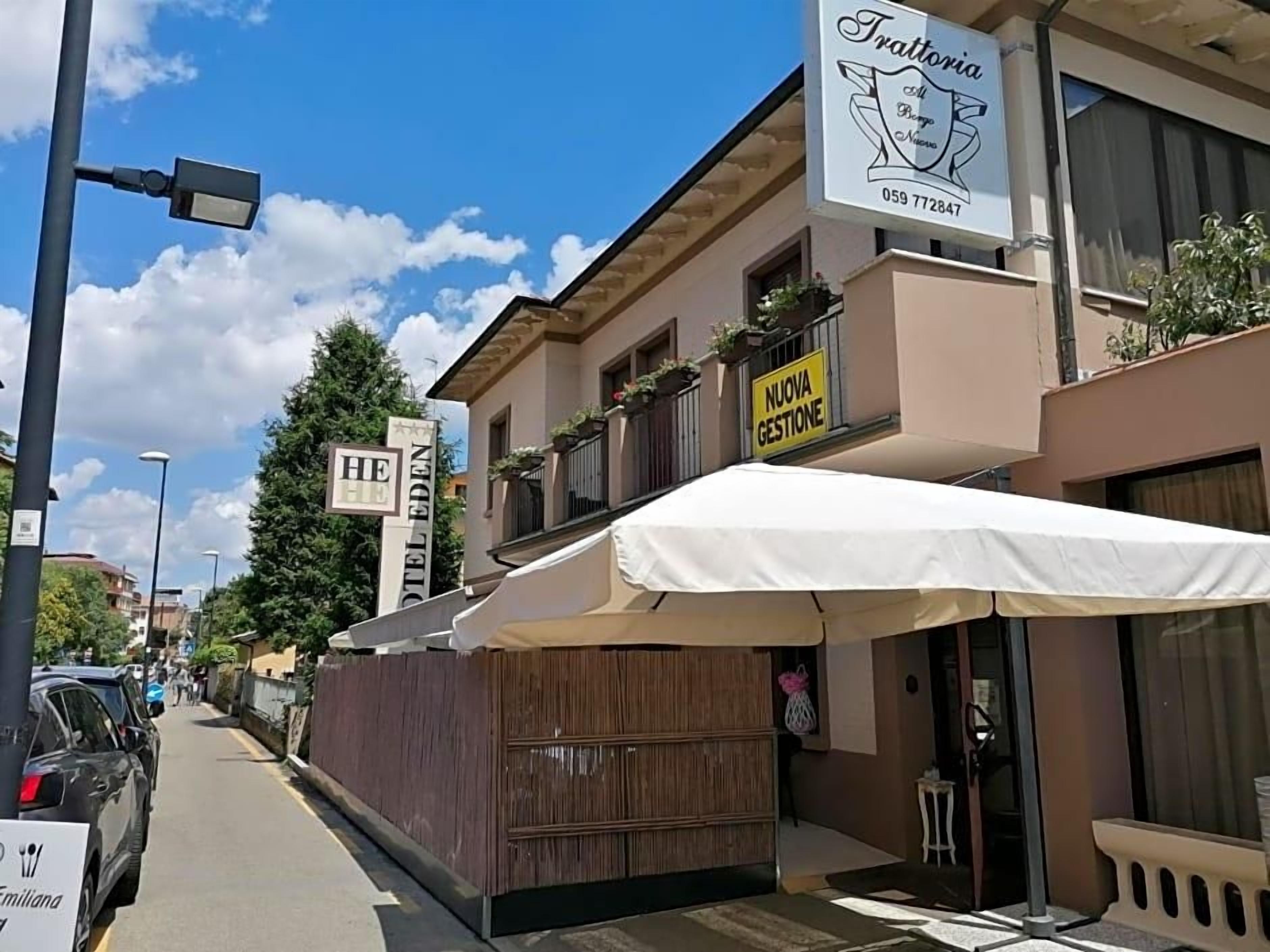 A building with a sign for 'Trattoria' and a 'Nuova Gestione' banner.