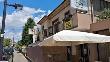 A building with a sign for 'Trattoria' and a 'Nuova Gestione' banner.