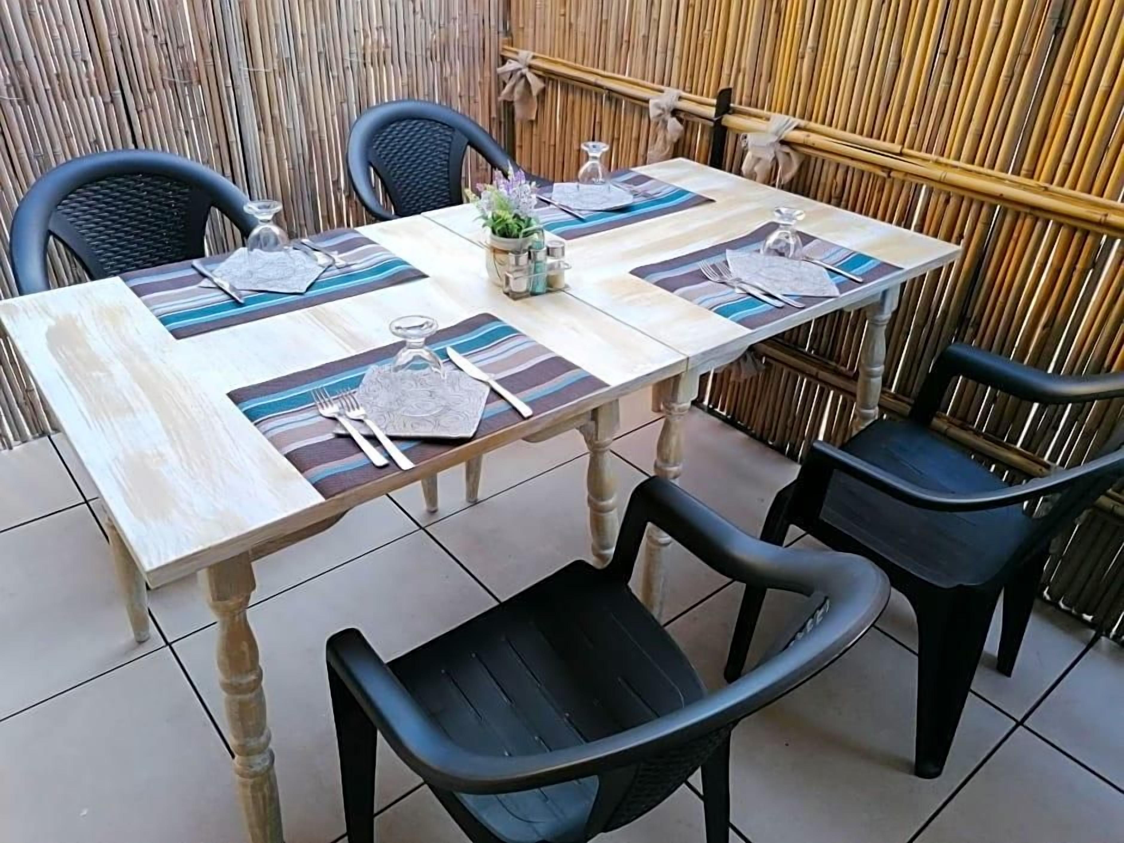 Een tafel voor vier met een bamboebachgrond, zwarte stoelen en strepen placemats.
