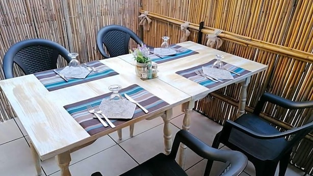 A table set for four with a bamboo backdrop, black chairs, and striped placemats.