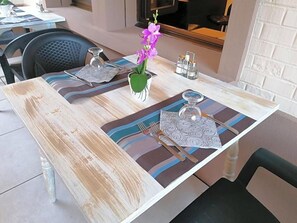 A dining table with placemats, a vase with flowers, and a candle holder.