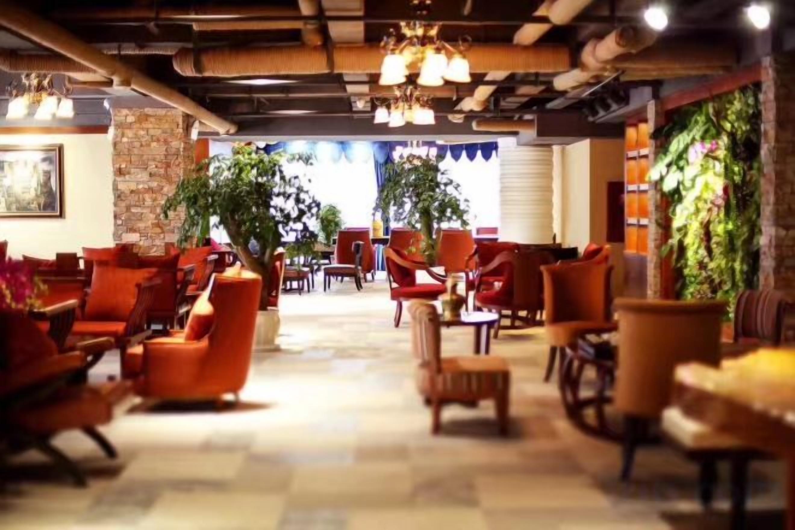Um hall de hotel com várias áreas de estar, incluindo sofás e cadeiras, dispostas em um espaço amplo.