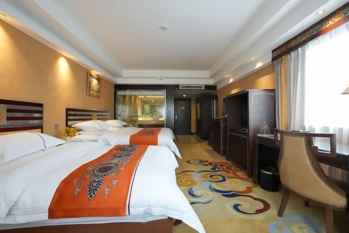 Een hotelkamer met twee bedden, een bureau, een stoel en een groot raam.