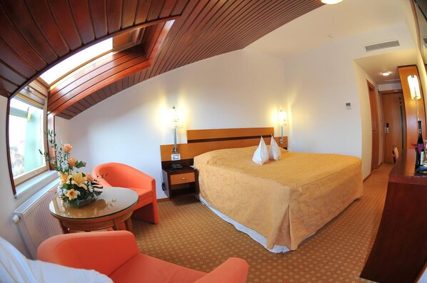 Une chambre d’hôtel avec un grand lit, un bureau, une chaise et une fenêtre.