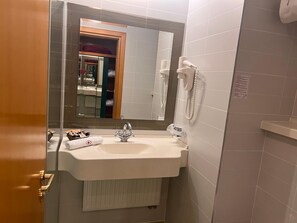 A bathroom with a white sink, a mirror, a towel, and a hairdryer.
