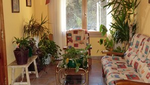 A cozy living room with a sofa, a chair, and various potted plants. - Pensión Malida (Vielha e Mijaran)