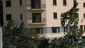 A multi-story building with a beige facade, multiple balconies, and a satellite dish. - Pensión Malida (Vielha e Mijaran)