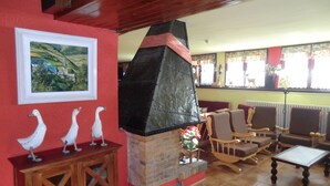 A cozy interior with a fireplace, wooden furniture, and a framed landscape painting. - Pensión Malida (Vielha e Mijaran)