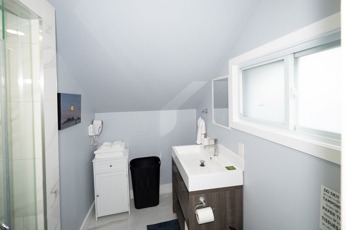 A bathroom with a white sink, a mirror, a towel rack, and a trash bin.